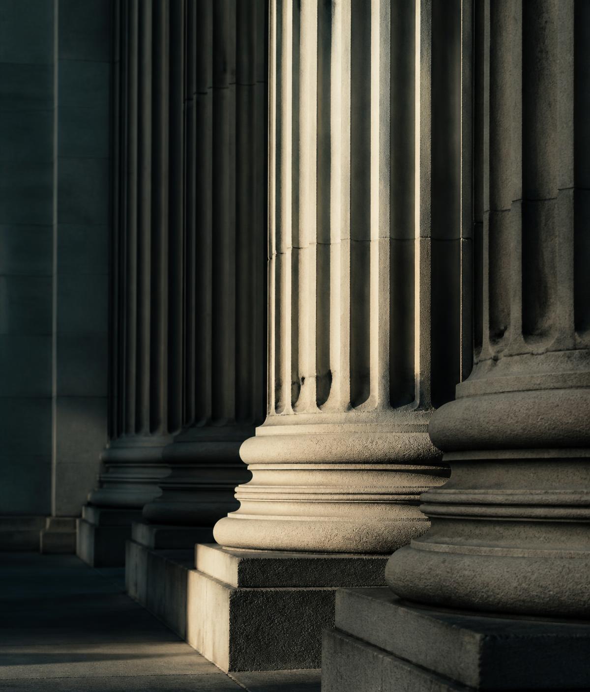 Stone colonnade of a courthouse in dramatic side light